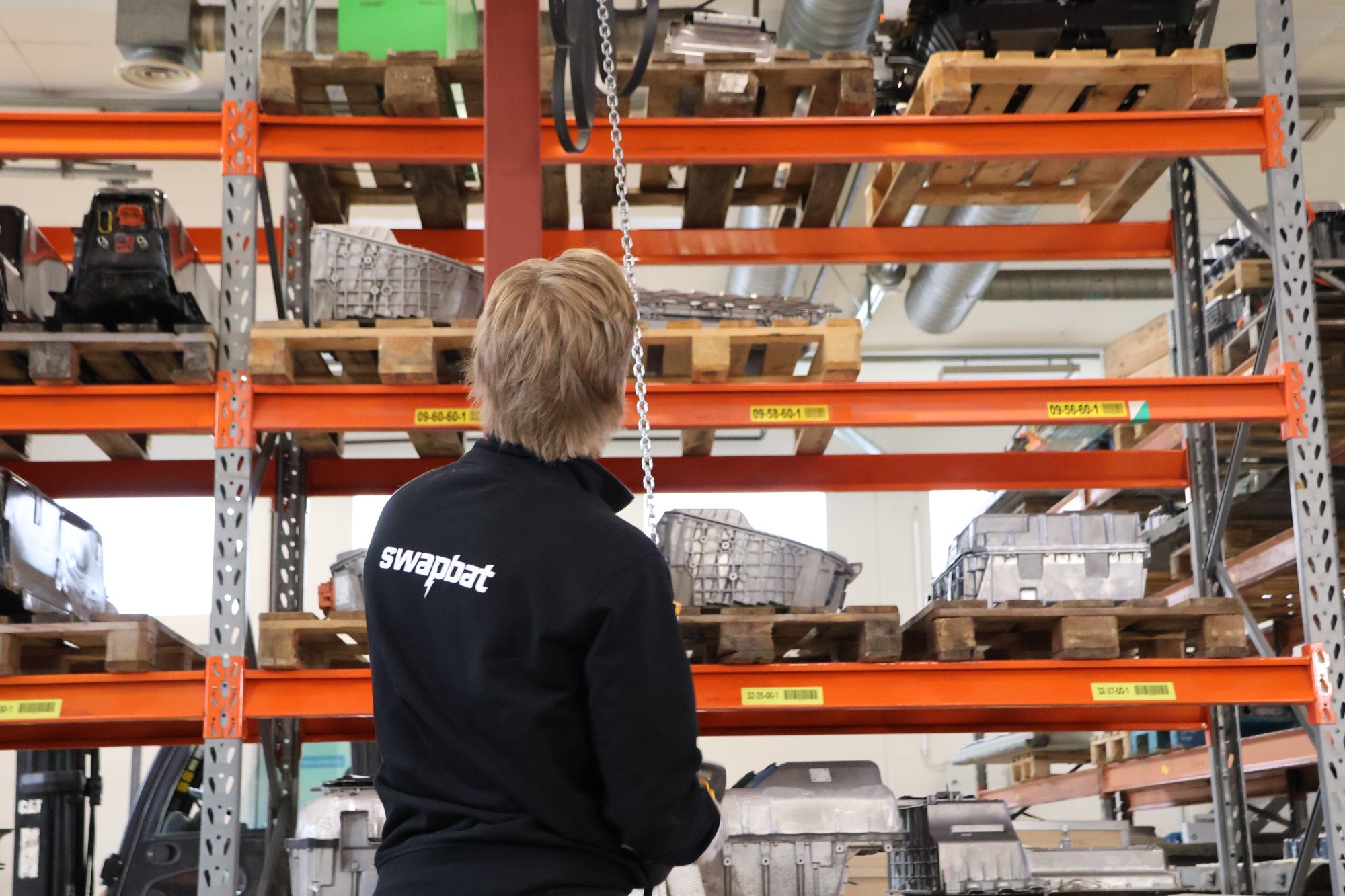 Swapbat technician at the Vantaa warehouse racking, stocked with high-voltage battery packs